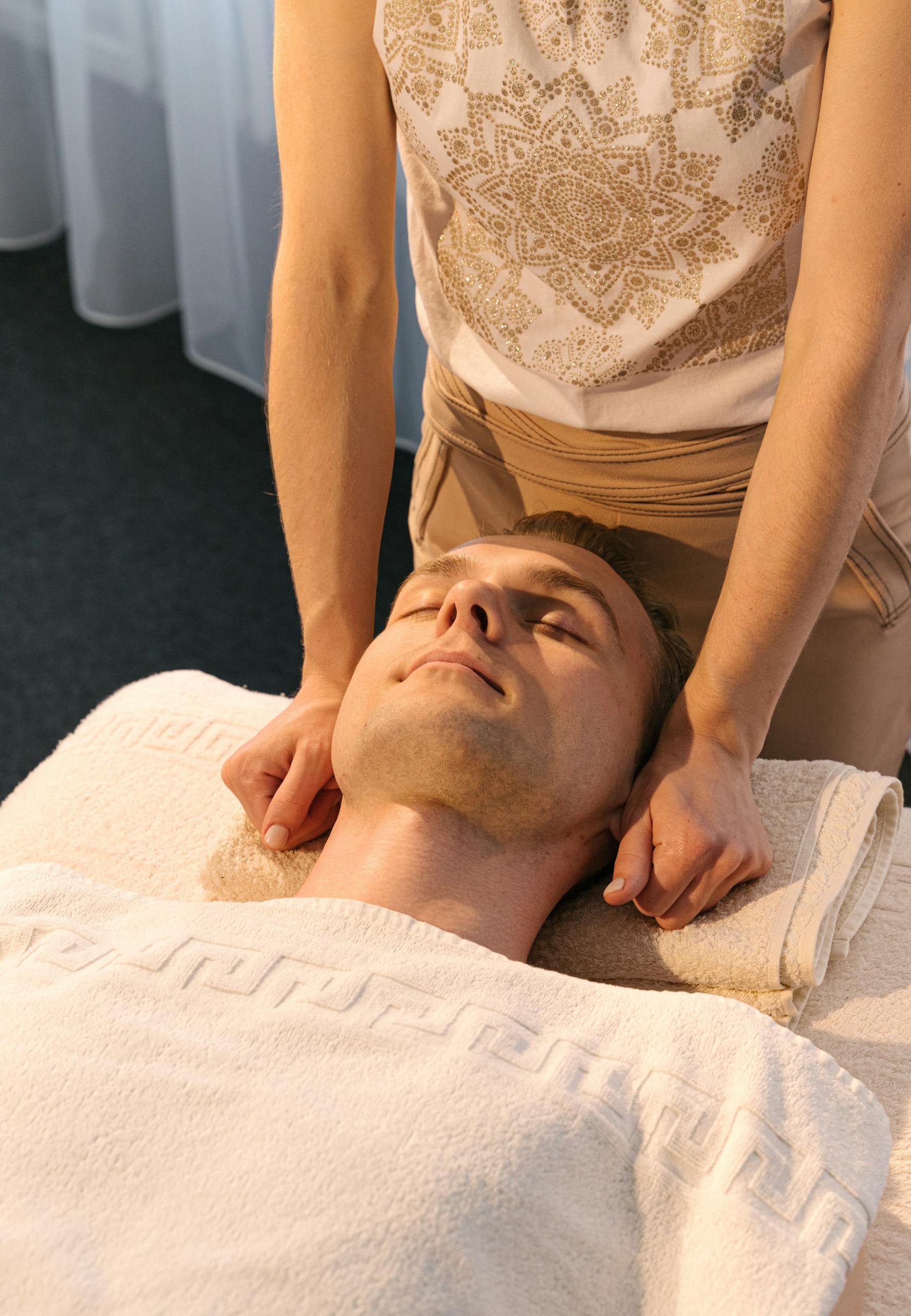 A man receiving a relaxing massage therapy session in a serene spa setting, promoting wellness.